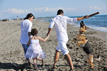 Image showing happy family playing with dog on beach