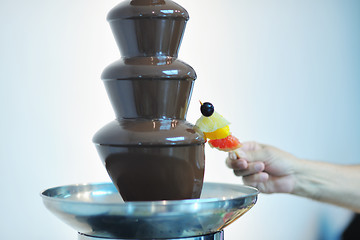 Image showing liquid chocolate fountain and fresh fruits on stick