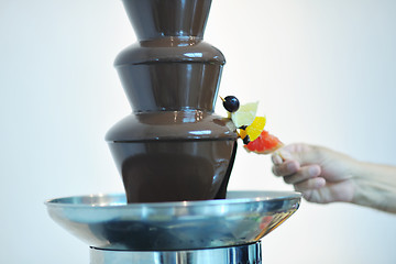 Image showing liquid chocolate fountain and fresh fruits on stick