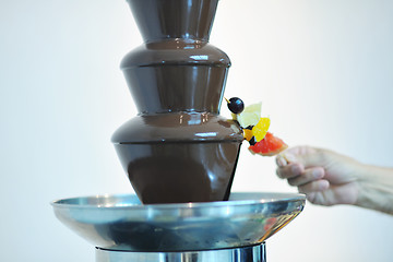 Image showing liquid chocolate fountain and fresh fruits on stick