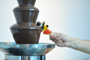 Image showing liquid chocolate fountain and fresh fruits on stick