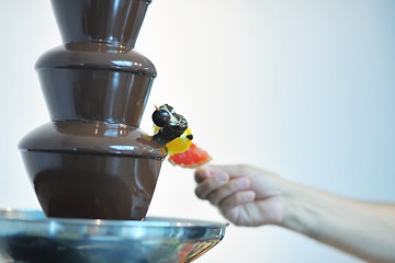 Image showing liquid chocolate fountain and fresh fruits on stick