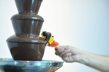 Image showing liquid chocolate fountain and fresh fruits on stick