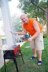 Image showing happy man preparing sausages on grill