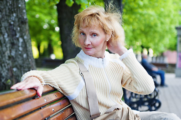 Image showing a middle-aged woman sits on a park bench