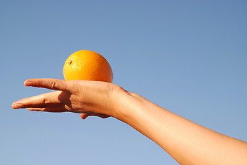 Image showing female hand balancing iorange in air