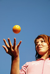 Image showing beautyful girl throwing orange in air