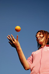 Image showing beautyful girl throwing orange in air