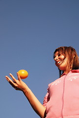 Image showing beautyful girl throwing orange in air
