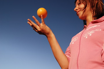 Image showing beautyful girl throwing orange in air