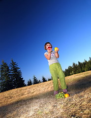 Image showing happy girl throwing apple outside