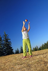 Image showing happy girl throwing apple outside