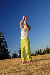 Image showing happy girl throwing apple outside