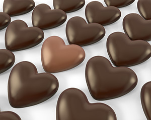 Image showing Heart shaped milk chocolate candy between dark ones