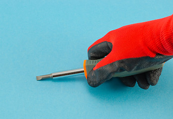 Image showing hand with orange gloves hold screwdriver on blue 