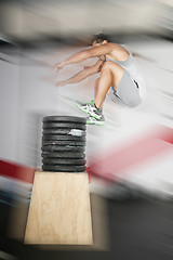 Image showing Athletic man jumping over a lot of weights 