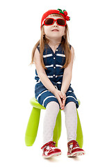 Image showing little girl in a red hat and sunglasses sitting on a green chair