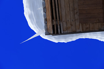 Image showing Snowdrift and big icicle on wooden roof