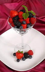 Image showing Fresh berries topped with mint in and around a martini glass