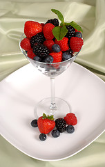 Image showing Fresh berries topped with mint in and around a martini glass res