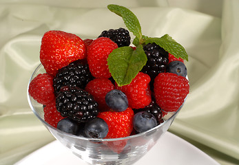 Image showing Close up of Fresh berries topped with mint in a martini glass re