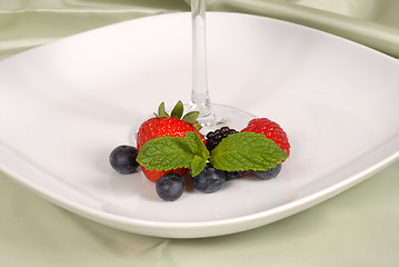 Image showing Fresh berries with mint surrounding the stem of a glass