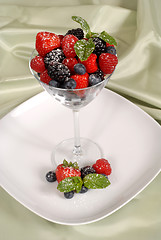 Image showing Fresh berries topped with mint and powdered sugar in and around