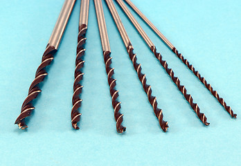 Image showing Various size wood drill bits for wood on blue 