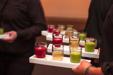 Image showing Servers holding colored shot glasses