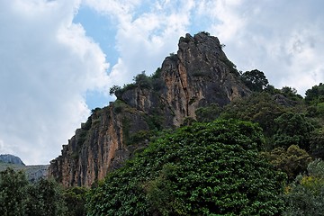 Image showing Black cliff towering above the forest