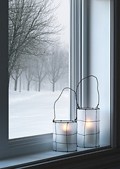 Image showing Cozy lanterns and winter landscape seen through the window