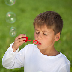 Image showing Boy having fun with bubbles on a green meadow