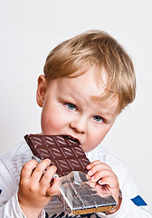 Image showing The little boy eats chocolate