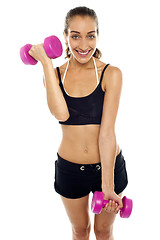 Image showing Smiling fit woman working out with dumbbells