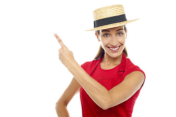 Image showing Smiling woman wearing straw bowler hat pointing away