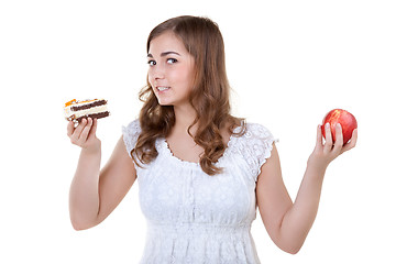 Image showing Young beautiful female choose from sweet cake and red apple