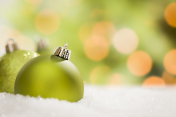 Image showing Green Christmas Ornaments on Snow Over an Abstract Background