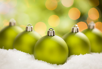 Image showing Green Christmas Ornaments on Snow Over an Abstract Background