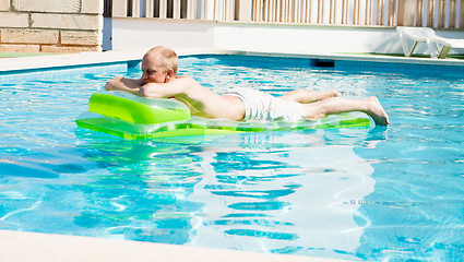 Image showing young man is swimming with air mattress in pool