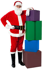 Image showing Santa Claus posing beside pile of gifts on Christmas eve