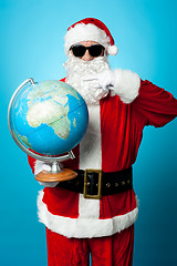 Image showing Stylish Santa in dark shades pointing at the globe