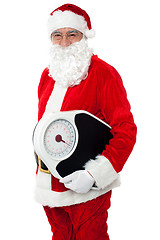 Image showing Aged male Santa holding weighing scale
