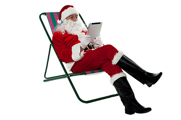 Image showing Kris Kringle relaxing and using electronic tablet