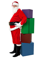 Image showing Santa leaning over colorful pile of Xmas presents