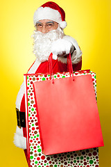 Image showing Cheerful Santa holding vibrant colored shopping bags