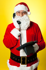 Image showing Smiling aged Santa attending phone call