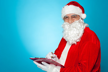 Image showing A thoroughly modern Santa claus checks his list on clipboard