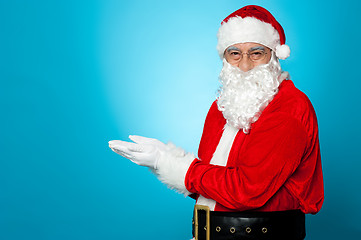 Image showing Santa against blue background posing with open palms