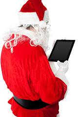 Image showing Back view of Santa looking at tablet device screen