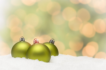 Image showing Green Christmas Ornaments on Snow Over an Abstract Background